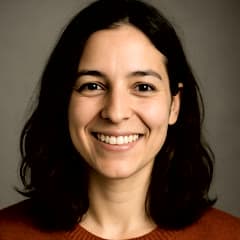 Retrato de una mujer joven de cabello oscuro, sonriendo de frente